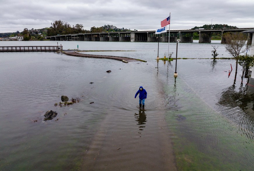 An aerial picture shows a man making his way along a flooded bike path in Mill Valley, California on Jan. 3, 2022.