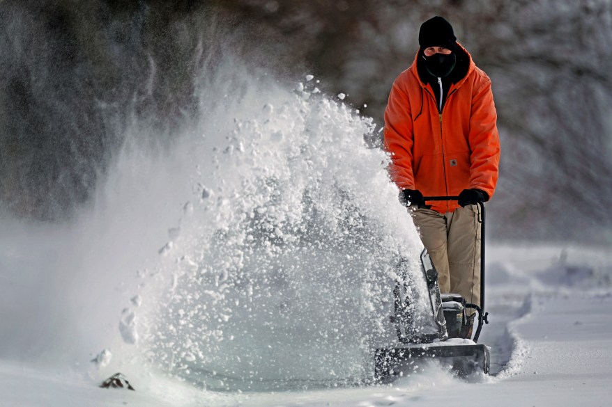 A man clears snow at his house on February 2, 2022, in Overland Park, Kansas after a major winter storm brought a mix of rain, freezing rain and snow to the central United States.