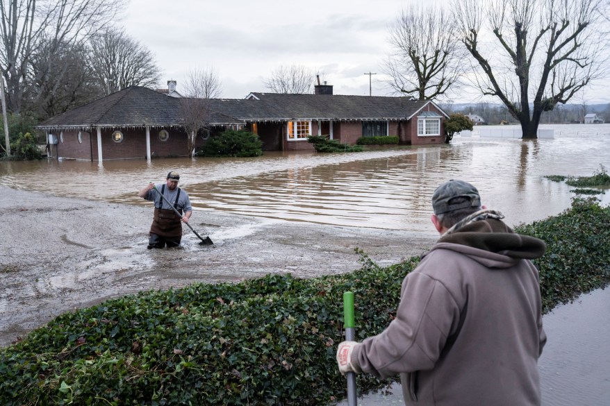 Two men attempt to redirect the flow of water as floodwaters threaten their homes after heavy rainfall in Chehalis, Washington on January 7, 2022.