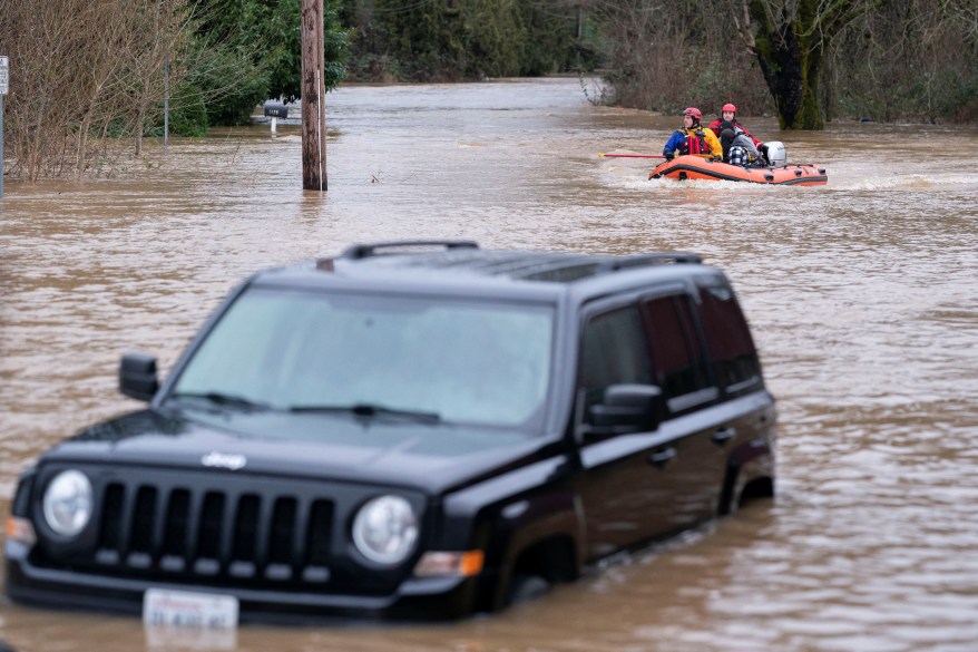 Chehalis fire and rescue team members bring a stranded resident to dry land after floodwaters engulf their car and threaten their home following heavy rain in Chehalis, Washington, on Jan. 7, 2022.