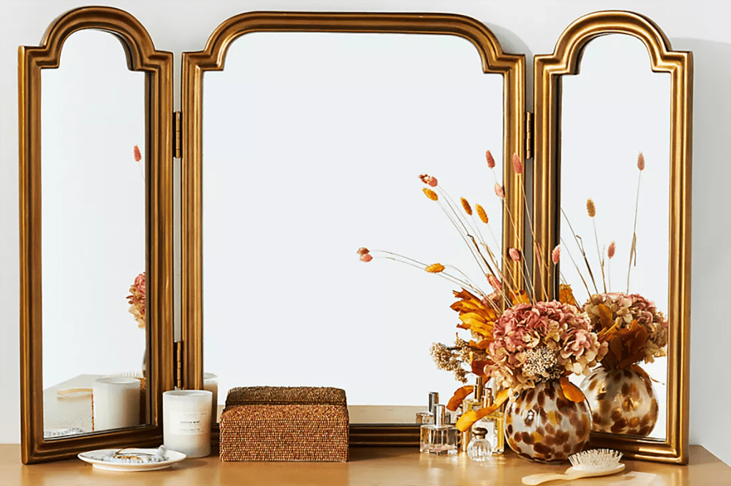 A trifold mirror sitting on a vanity 