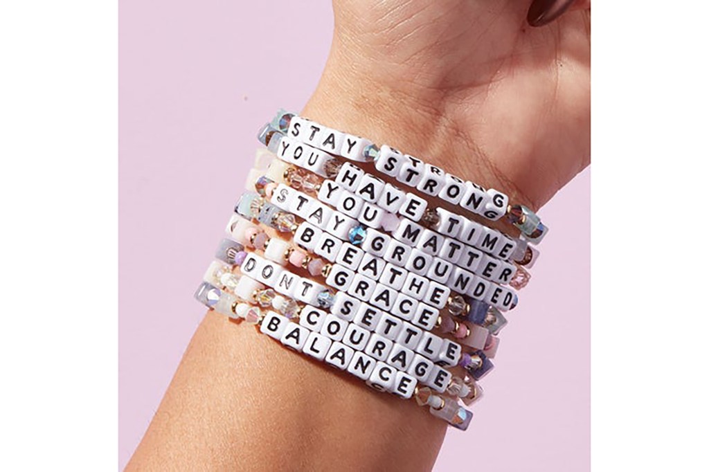 An arm with a stack of bracelets on it with empowering messages 