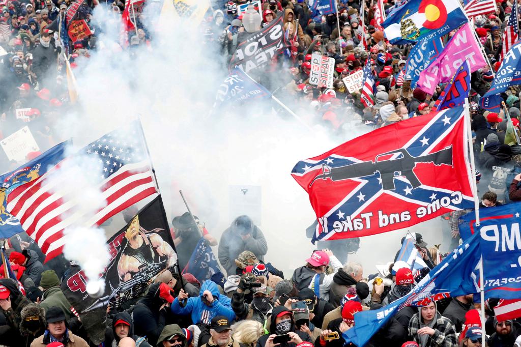 Tear gas is released into a crowd of protesters, with one wielding a Confederate battle flag that reads "Come and Take It," during clashes with Capitol police on January 6, 2021.