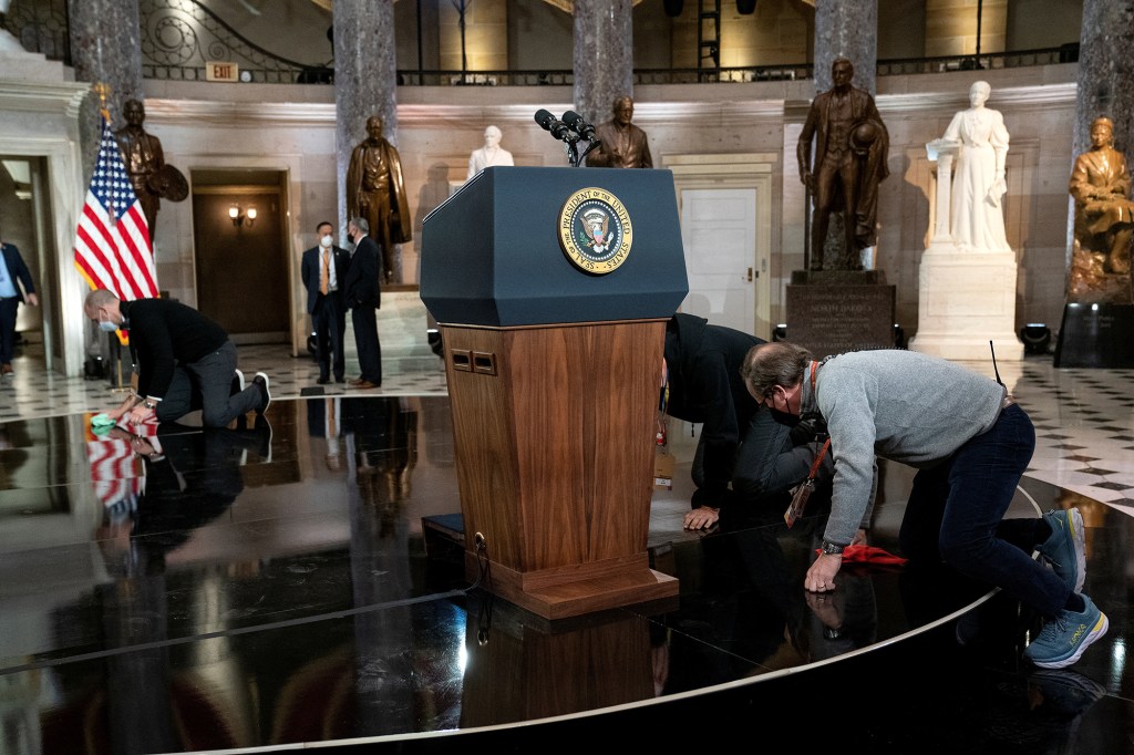 Workers clean the stage where U.S. President Joe Biden and Vice President Kamala Harris will give remarks on the first anniversary of the January 6, 2021 attack on the Capitol