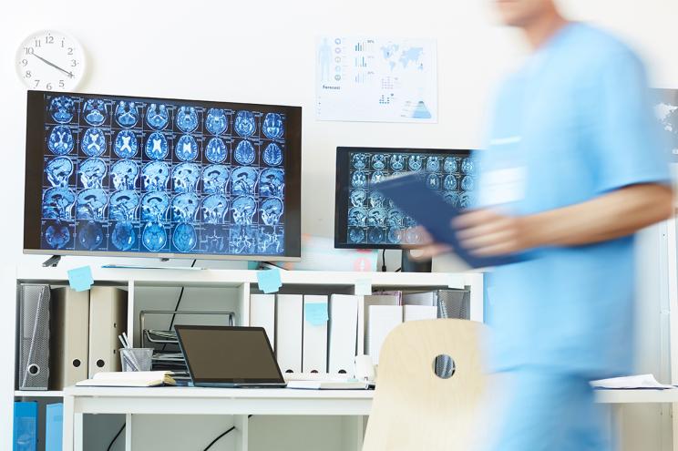 Background image of modern computer equipment with CT brain scans on screens