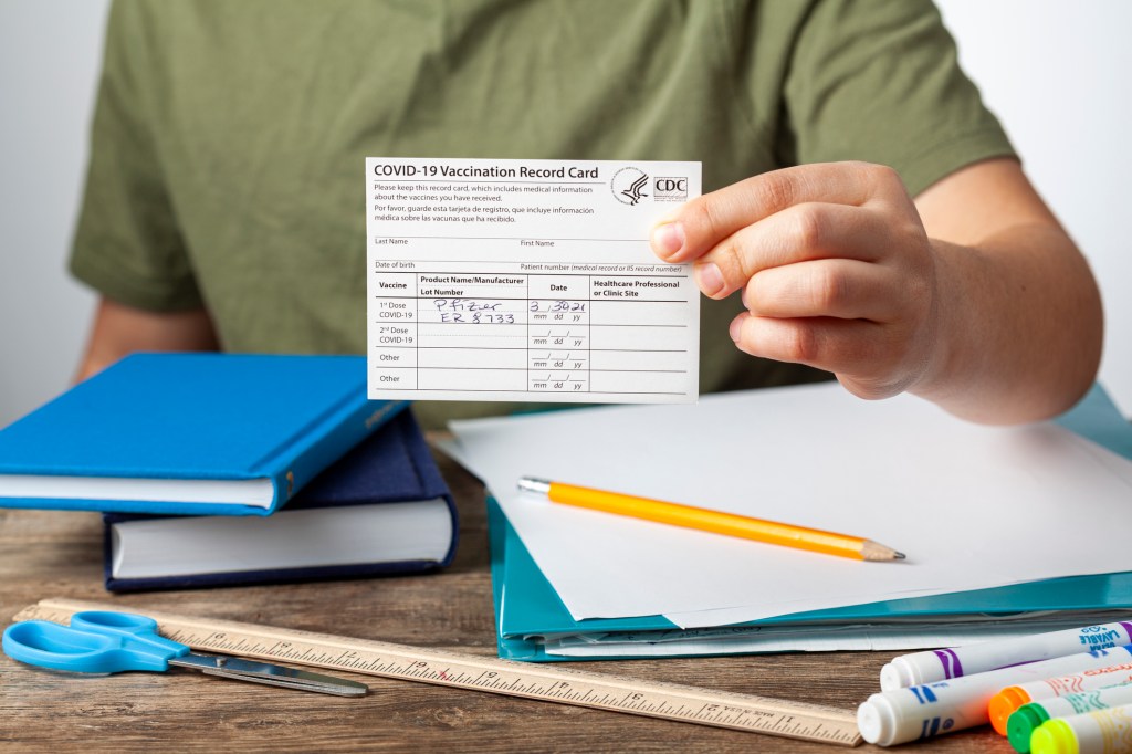 Child holding COVID vaccination card.