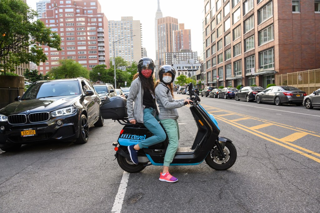 Medical workers ride a Revel scooter.