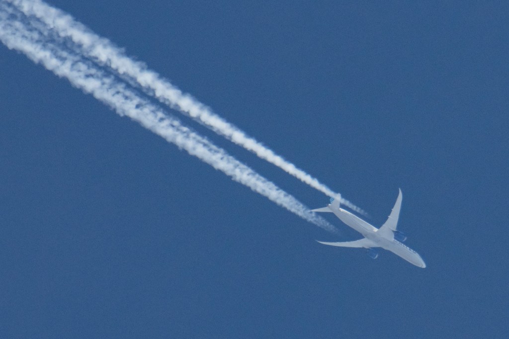 A United Airlines Boeing 787 Dreamliner airplane is seen overflying in the blue sky over Amsterdam.