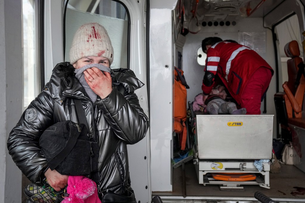 A woman reacts as paramedics perform CPR on a girl who was injured during shelling.