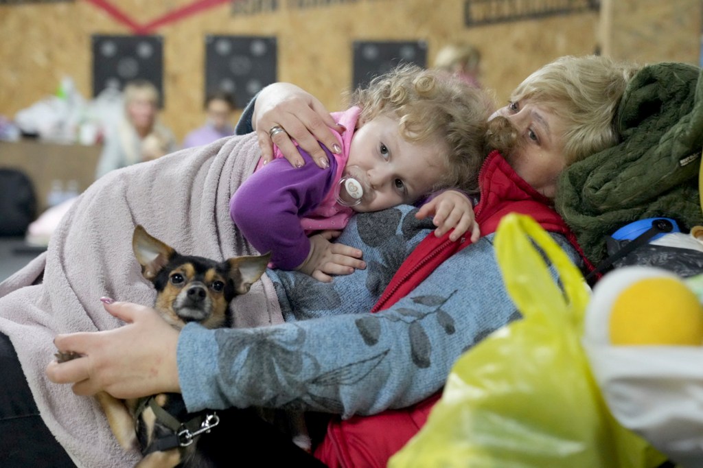 A women holds a child and a dog in a shelter inside a building in Mariupol, Ukraine.