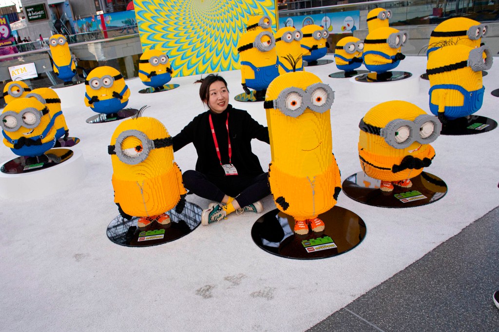 A woman sitting amongst large, yellow Minion toys.