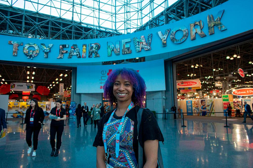 An attendee standing in front of the Toy Fair banner inside Javits Center.