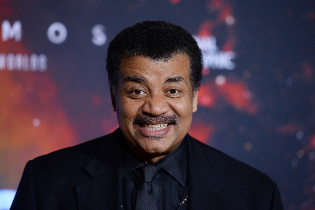 Neil deGrasse Tyson smiles in a black suit