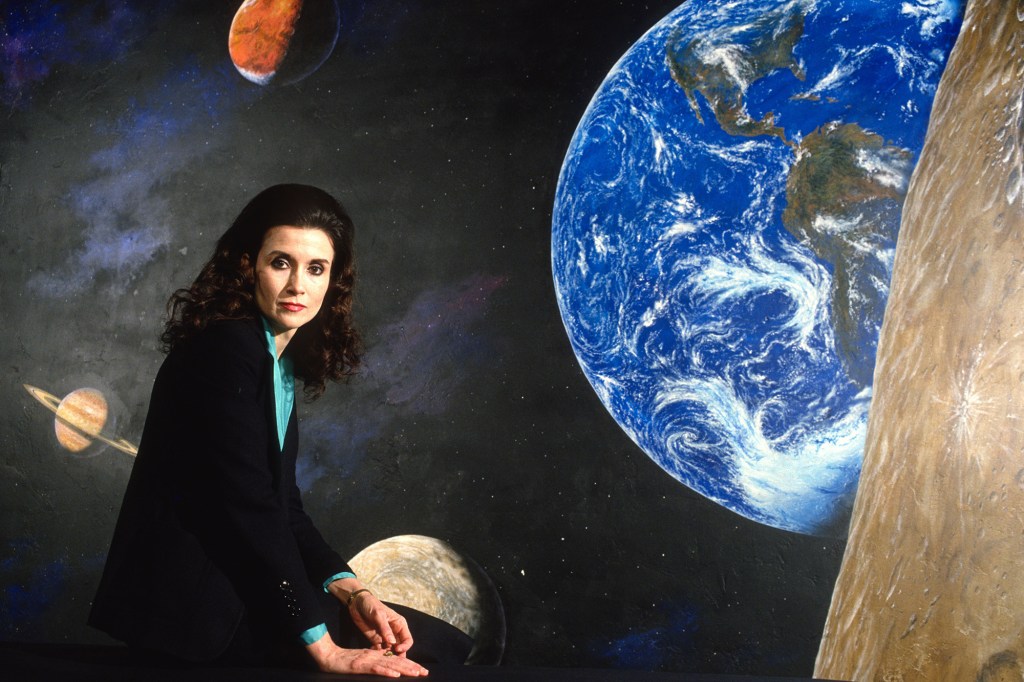 Marilyn vos Savant poses in front of an image of the solar system