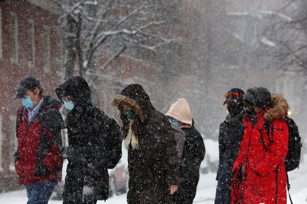 Pedestrians walk through falling snow during a winter storm in Boston, Massachusetts, U.S., February 25, 2022.