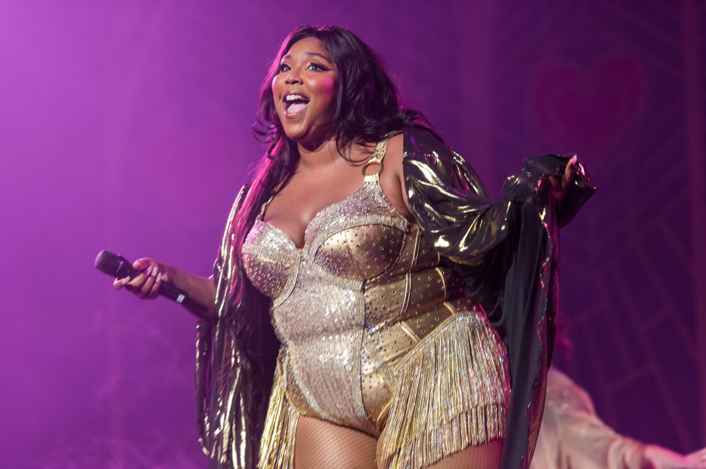 Lizzo onstage in a gold corset and cape.