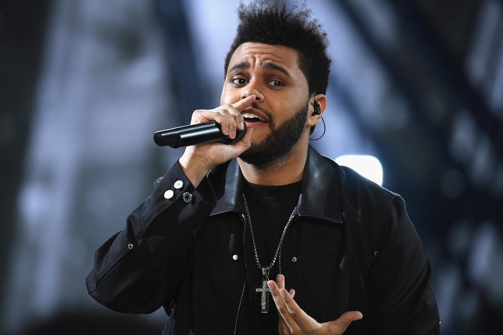 The Weeknd performs onstage in a black jacket.