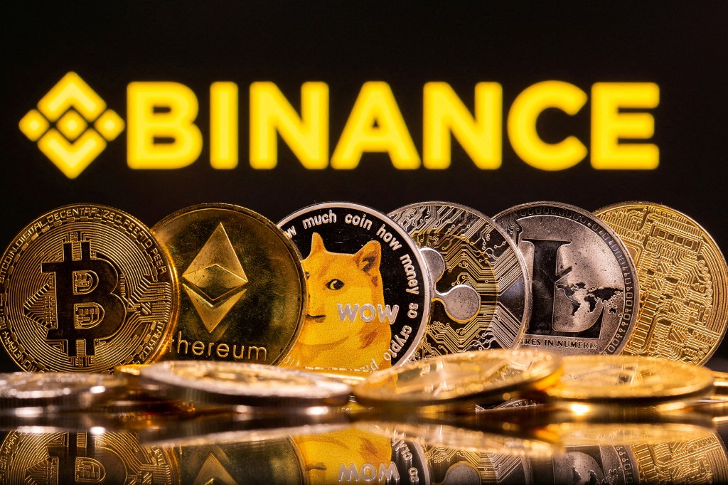 Representations of cryptocurrencies Bitcoin, Ethereum, DogeCoin, Ripple, and Litecoin are seen in front of a displayed Binance logo in this illustration taken, June 28, 2021.