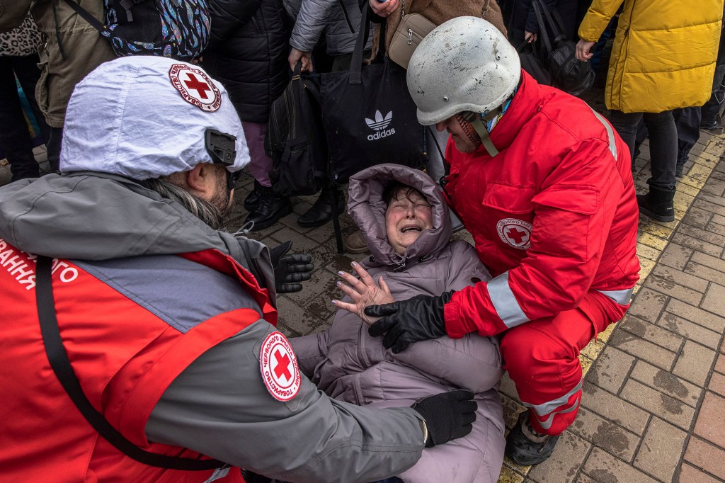 Members of Red Cross help a woman as she reacts after an evacuation train left to the city of Kyiv.