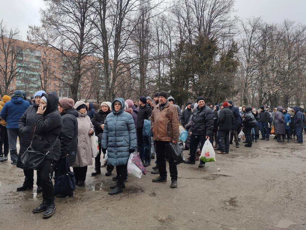 Local residents queue to receive food at the territory of a hospital.