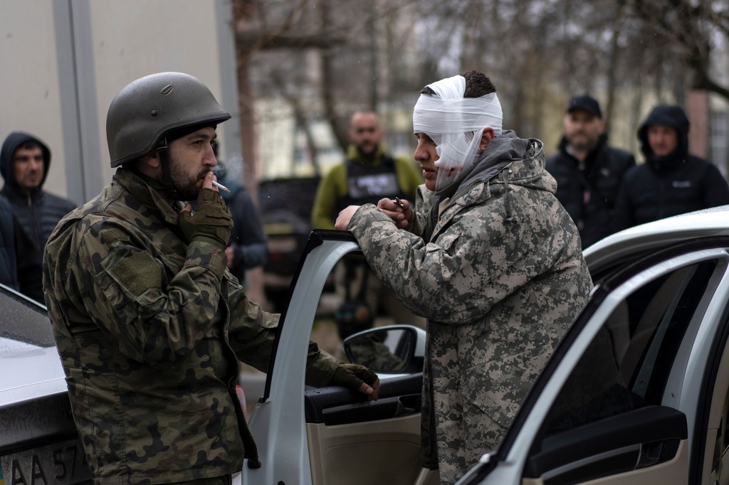 A wounded man talks to a soldier, left, after being evacuated from Irpin, on the outskirts of Kyiv, Ukraine, Wednesday, March 30, 2022.