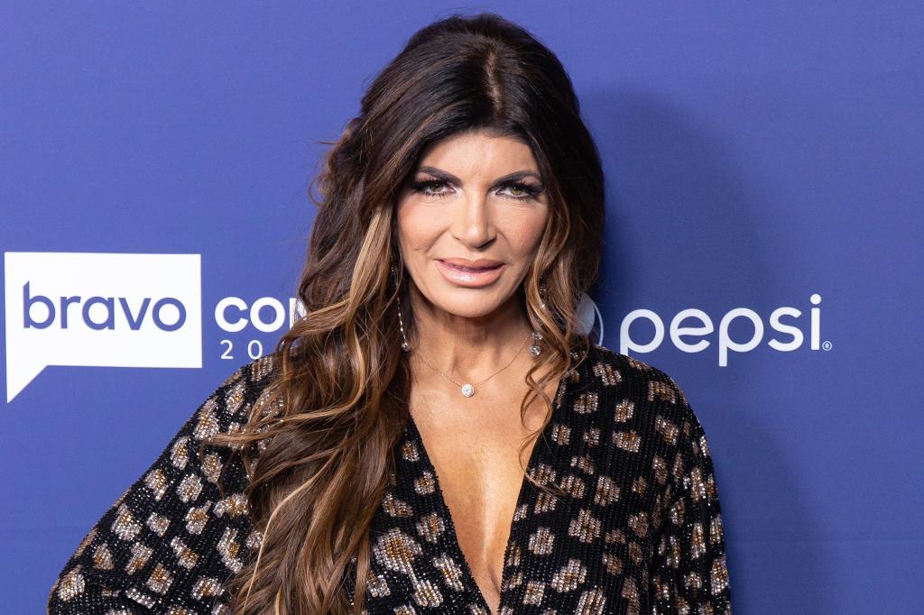 Teresa Giudice in a low cut black top against a blue background.