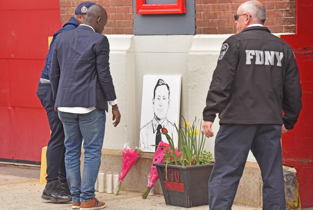 People gather near a makeshift memorial at the bunting ceremony for fire fighter Timothy Klein after he was killed in a three-alarm fire.  