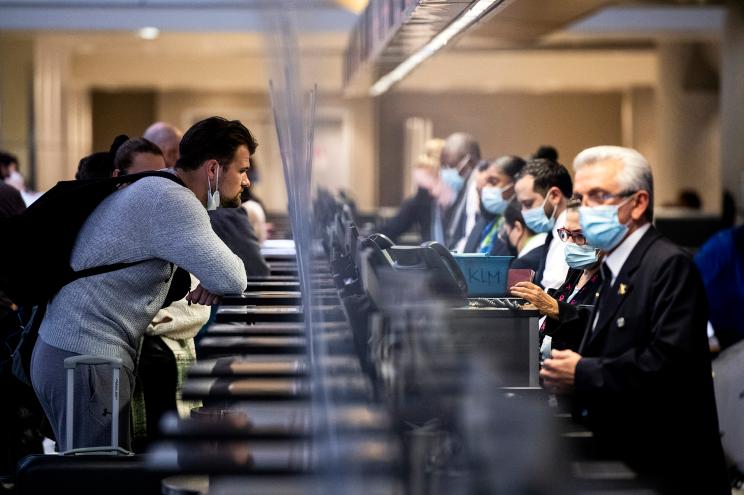 A maskless passenger interacts with a masked employee at the International flights terminal of the Los Angeles Airport.