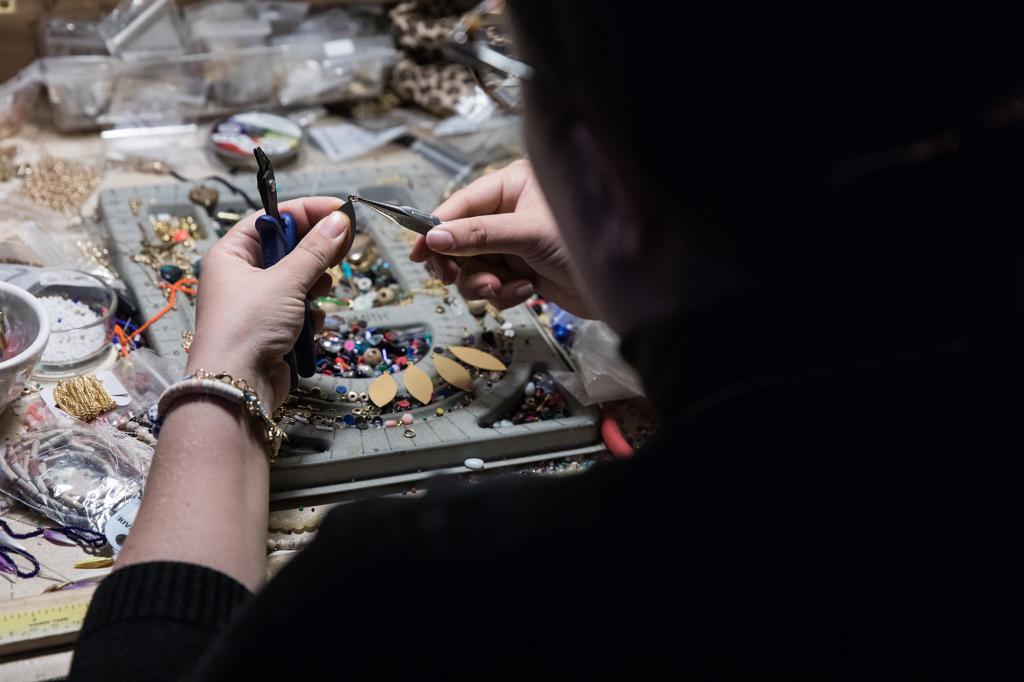 A person putting together jewelry made from beads.