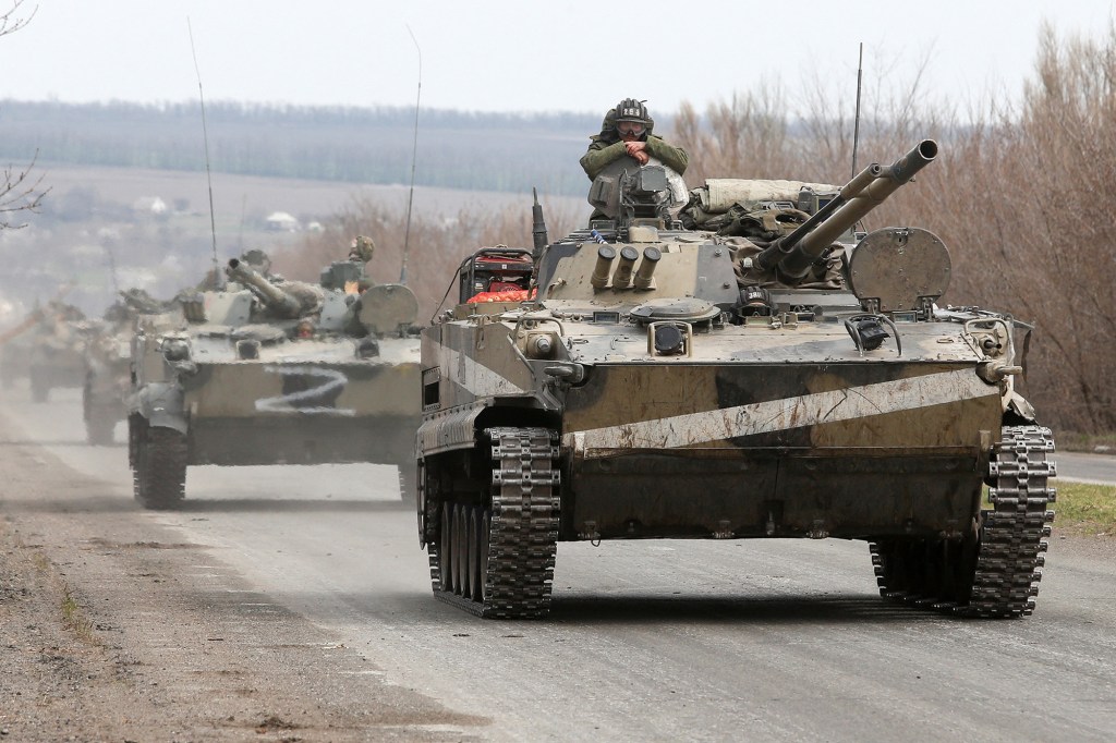 Service members of pro-Russian troops drive armored vehicles.