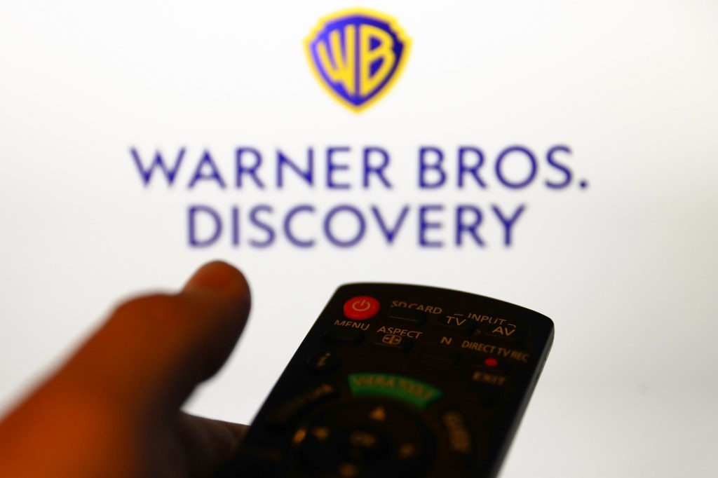 Warner Bros. Discovery logo displayed on a screen and a tv remote control