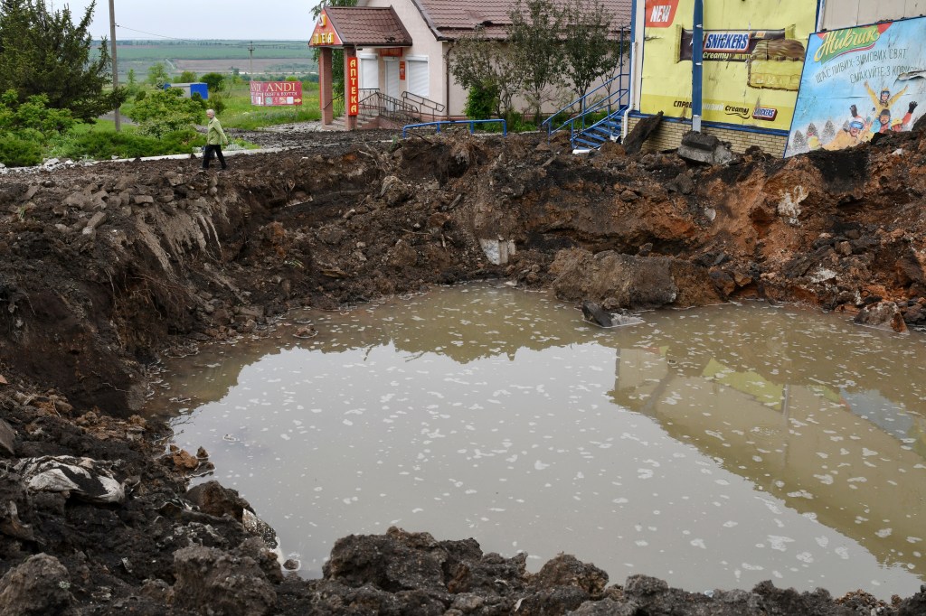 A woman walks past a crater of an explosion in Soledar, Donetsk region of Ukraine on May 18, 2022.