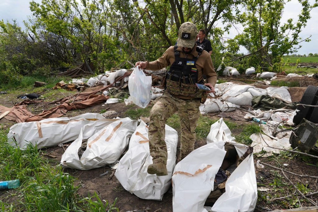 A Ukrainian serviceman works during the exhumation of killed Russian soldiers' at their near the village of Malaya Rohan, on the outskirts of Kharkiv on May 18, 2022. 