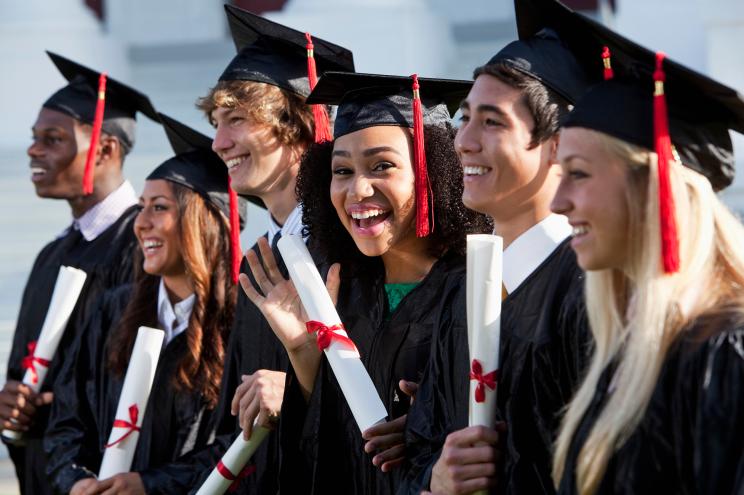 Multi-ethnic friends graduating together, in cap and gown.