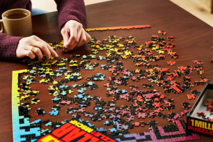 Hands putting together a rainbow puzzle on a table