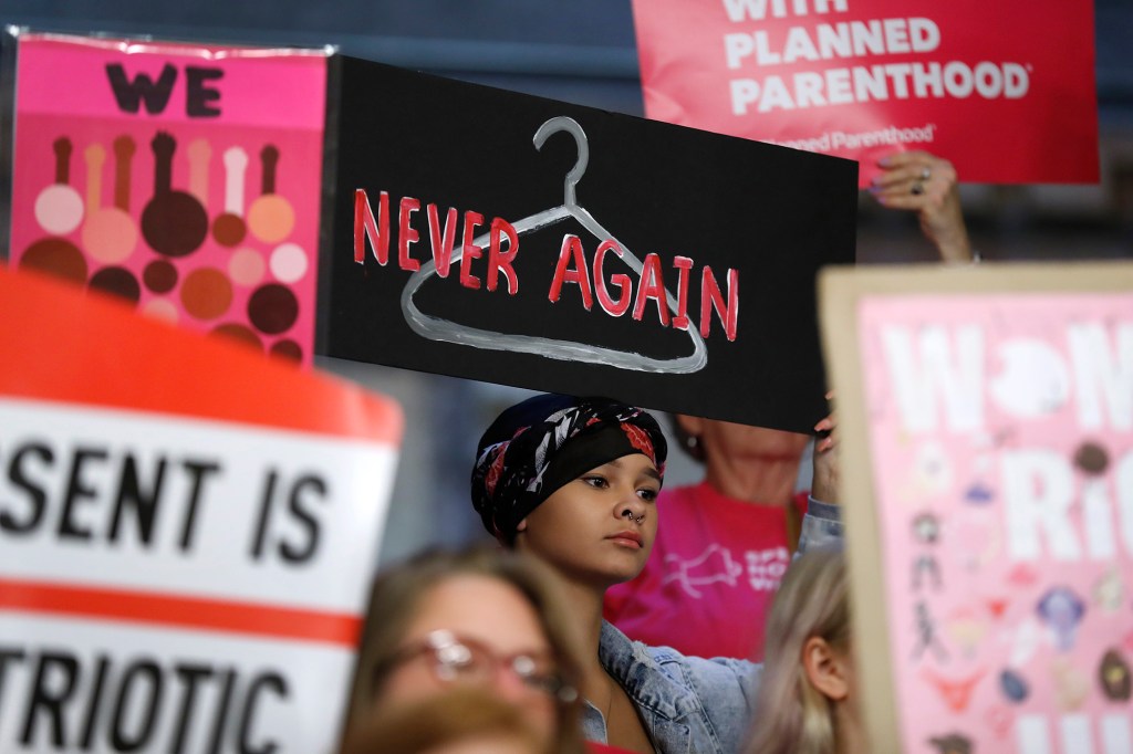 August Mulvihill, of Norwalk, Iowa, center, holds a sign during a rally to protest recent abortion bans, Tuesday, May 21, 2019, at the Statehouse in Des Moines, Iowa.