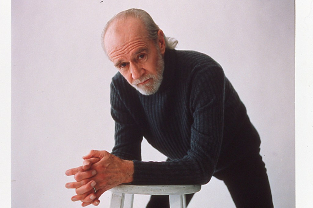 "George Carlin's American Dream" takes a comprehensive look at the late comedian's life. Photo shows George Carlin in his later years, with a grey beard. He's wearing a sweater and leaning on a chair.