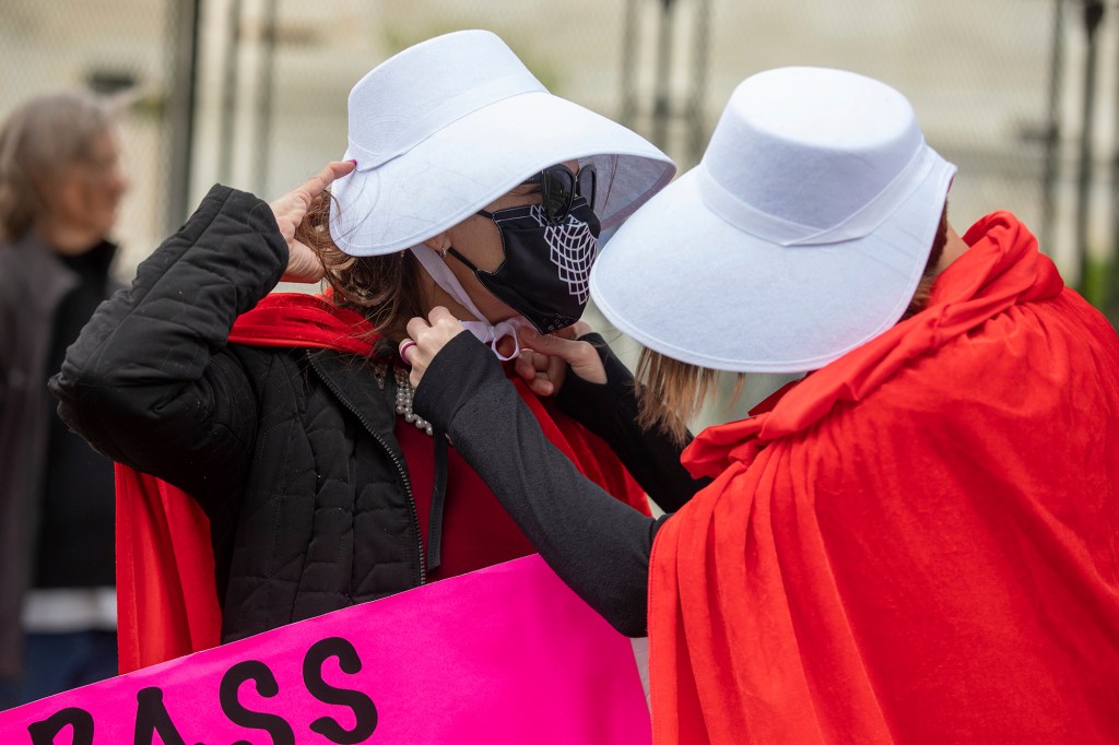 Abortion-rights protesters dressed in costumes from the "Handmaid's Tale" help each other adjust their bonnets during a demonstration outside of the U.S. Supreme Court.