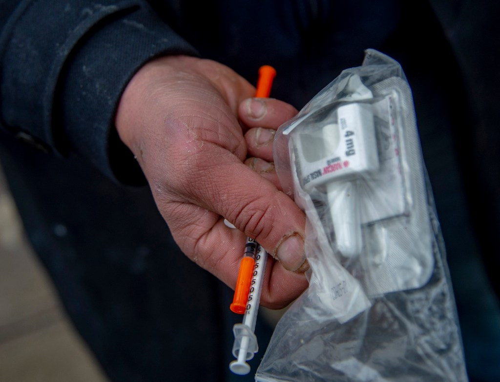 Jordan S. shows his fresh needles, Narcan, and a Sharps box in front of the Care Van on 181st street in Manhattan.