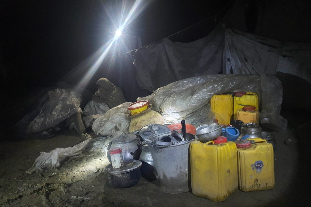 A woman sits inky a makeshift shelter in the village of Gyan, in Paktika province, Afghanistan.