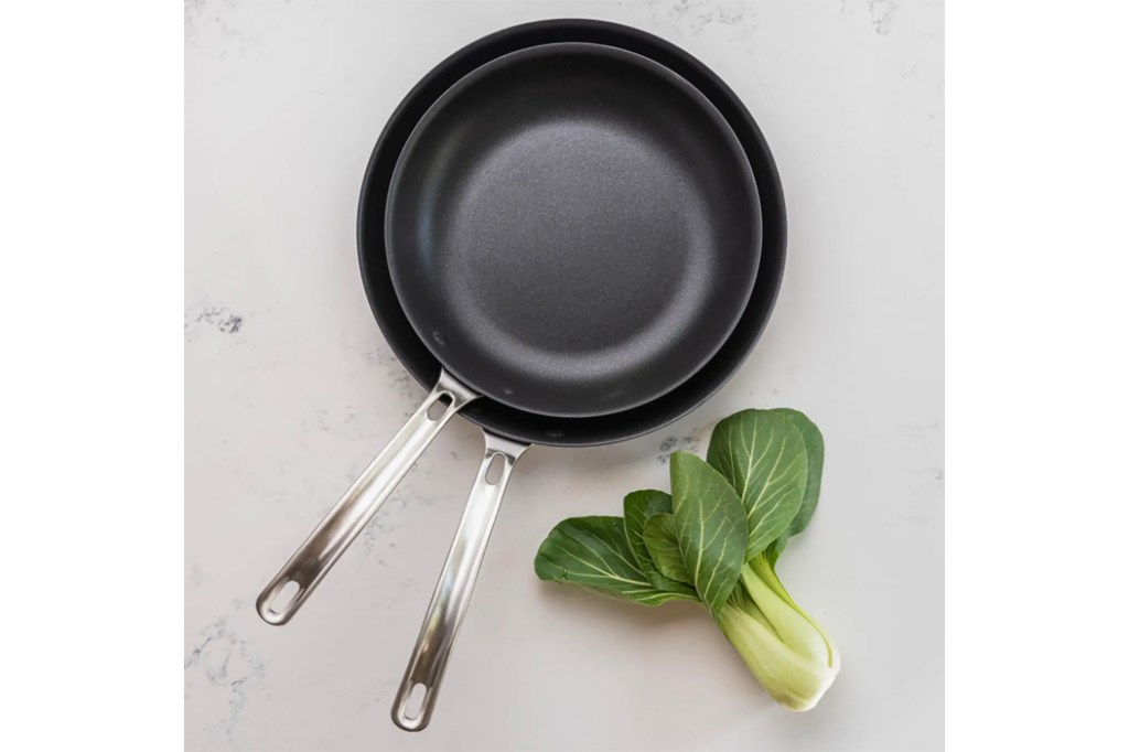 A stack of two black pans and a leek 