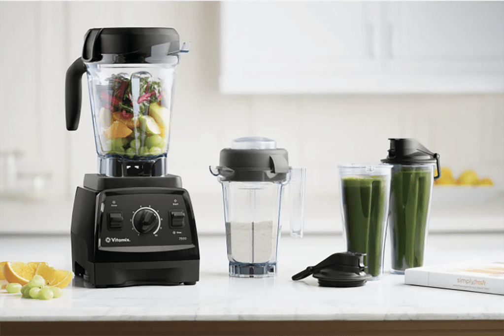 A black Vitamix blender and a cup with green juice 