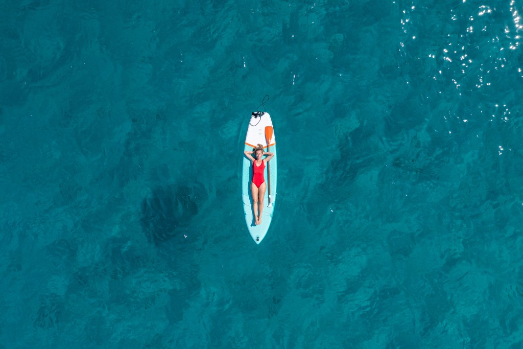 She lies down on a  paddle board and enjoys relaxation on tropical turquoise lagoon