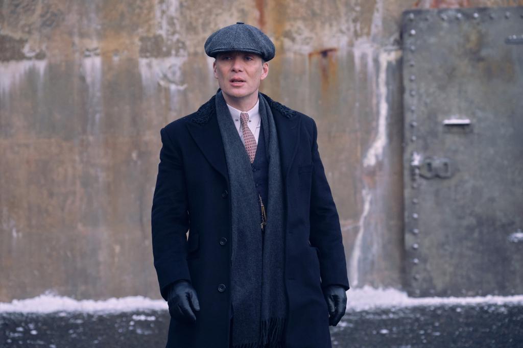 Cillian Murphy wearing a Peaky Blinders hat, looking stern.