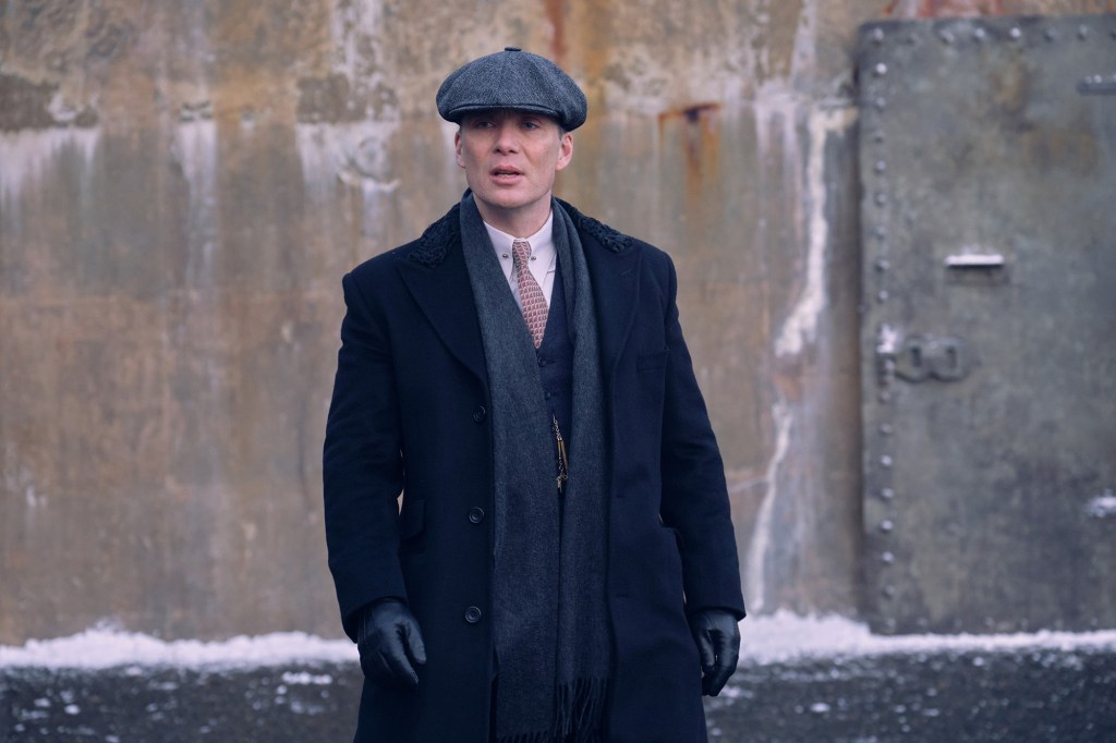 Cillian Murphy wearing a Peaky Blinders hat, looking stern. 