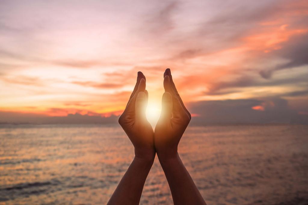 June summer sun solstice concept with silhouette of happy young woman's hands relaxing, meditating and holding sunset against warm golden hour sky on the beach with natural ocean or sea background