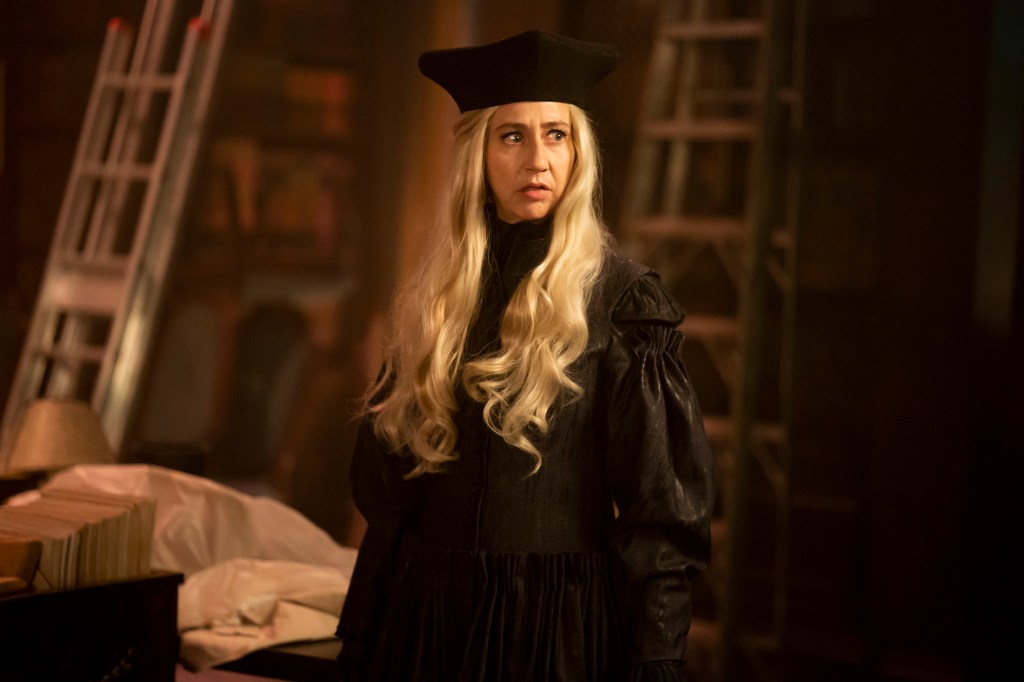 Photo of Kristen Schaal as The Guide in Season 4 of "What We Do in the Shadows." She's dressed in black and is wearing a black hat. Her hair is blond.