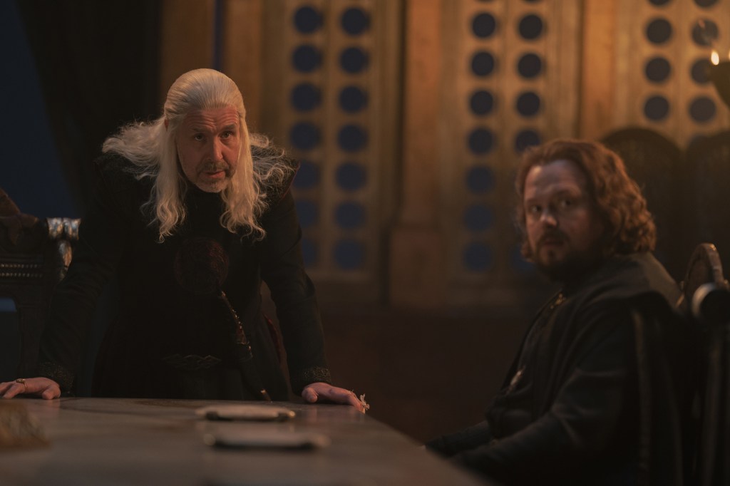 King Viserys (Paddy Considine), leaning over a table looking tense. 