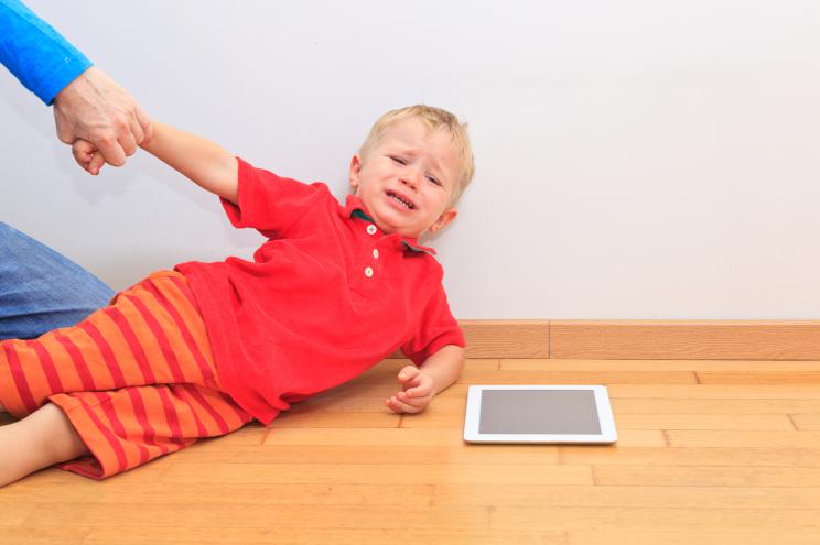 Parent pulling child from touch ipad.