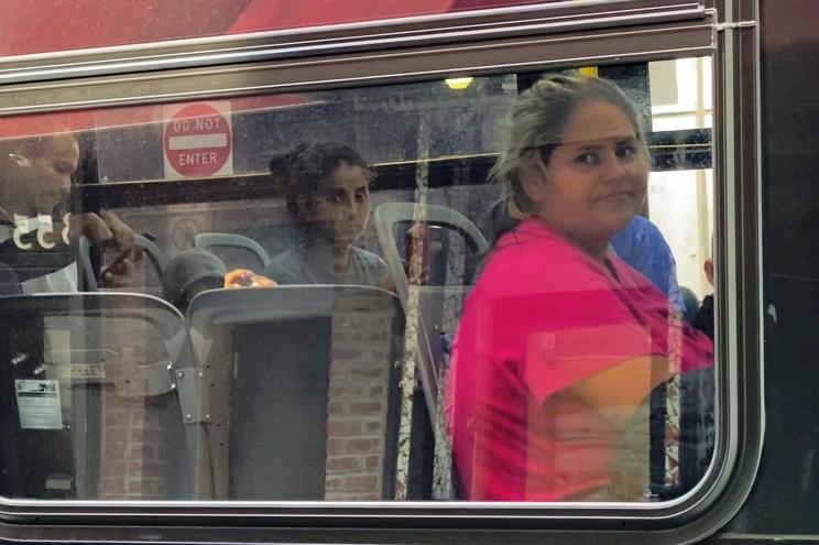 Migrants look on as they are bused from Port Authority bus terminal.